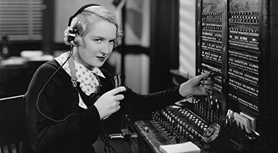 Opératrice téléphonique travaillant sur la console d’un central téléphonique dans les années 30 (noir et blanc)