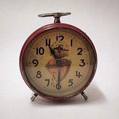 Alarm clock with a painted Sacred Heart motif behind the hands.