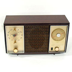 Wood and metal clock radio with a clock face, a frequency tuner and a speaker.