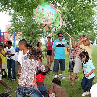 Children and adults of different cultures celebrate a birthday around a piñata.