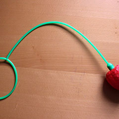 Jouet pour enfant nommé cloche-pied. La cloche est ici a la forme d'une fraise.