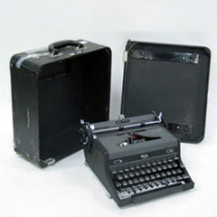 Une machine à écrire et sa boîte de transport.