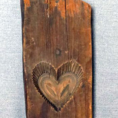 Moule à sucre fait en bois, vers 1900. Un coeur est taillé au centre de la planche de bois.