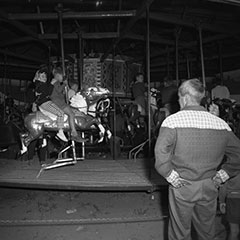 Des enfants s'amusent dans un carrousel alors qu'un homme les surveille.