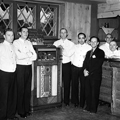 Des serveurs et monsieur Louis Faust se tiennent près du juke-box Wurlitzer dans un hôtel de Sainte-Adèle.